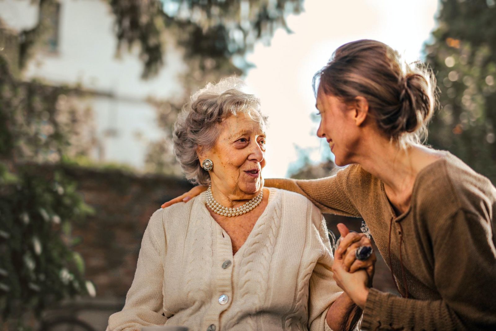 An elderly woman smiling while speaking with a loved one
